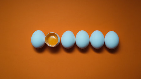 Row White eggs and egg yolk on the yellow background. Egg yolk in egg shell, cracked egg white...