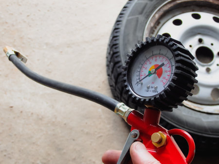 Checking Tire Pressure. Hand holding machine Inflated pressure gauge for car tire pressure measurement for automobile wheels. Air compressor gun with pressure gaugeの写真素材