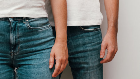 Young couple in jeans. Heterosexual couple hands. mid section. Close-up of man and woman hands stand together. Caucasian, lovely, cute, adult couple in casual outfit standing next to each otherの写真素材