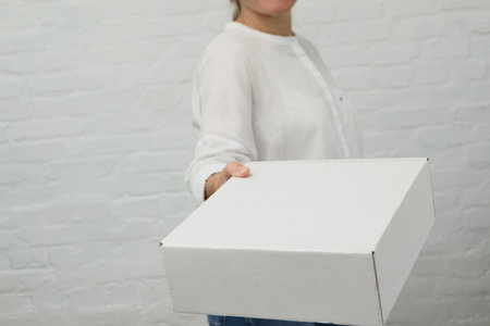 Woman giving parcel on white background. Delivery, relocation and unpacking. Woman hands with...