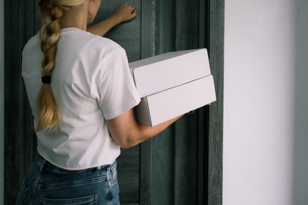 Delivery service. Woman with boxes for delivery, shipping package or ecommerce logistics at the door.の写真素材