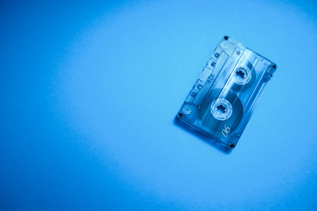 Old vintage transparent audio cassette tape photo on blue background. Place for text.の写真素材