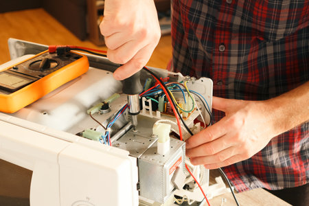 A repair engineer disassembles a microwave oven looking for a fault.の写真素材