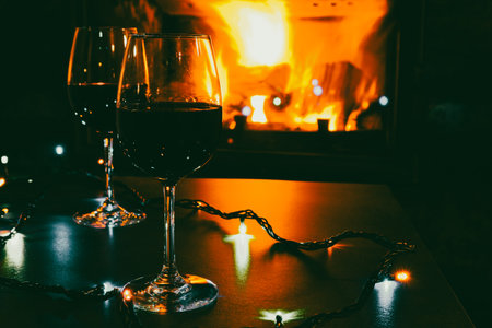 Two glasses of red wine against the background of a burning fireplace in hard reflective lighting....
