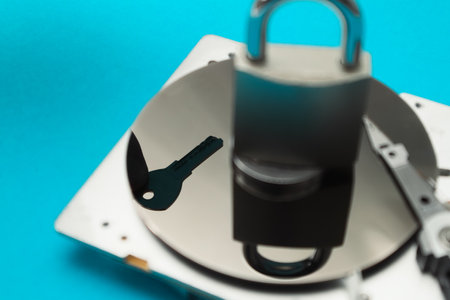 Password and data protection concept. A disassembled hard drive, pad lock and key in the hands of a hacker. Cyber security concept with a padlock on hard disk. Blocked storage deviceの写真素材