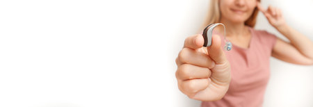 Woman holding a hearing aid on white background. A joyful woman can hear the sounds of the world...