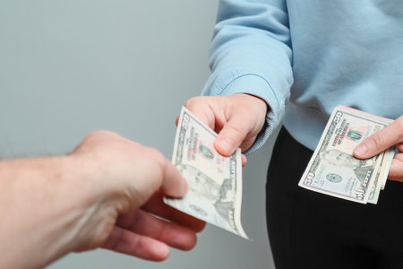 A woman gives paper American dollar bills. Cash. Pay someone with dollars. Bribery and corruption...