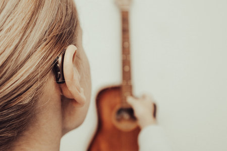 A woman with a hearing aid plays the guitar. I can hear music again. Technologies to assist people with disabilities.の写真素材