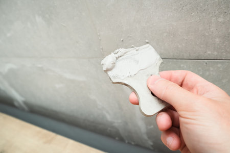 Grouting ceramic tiles using a fugue. Worker putting fugue on tiles closeup. tiles renovationの写真素材