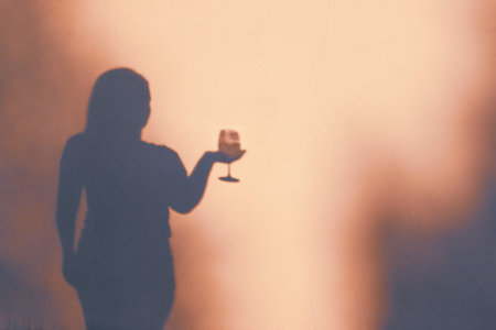 Woman holding glass of wine. Shadow Silhouette of female holding wine. Woman having fun on a partyの写真素材