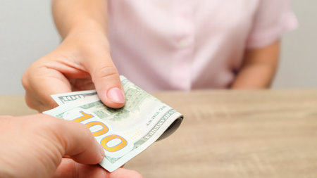 Hand Giving Money. Cash turnover. Man gives banknotes to woman. Dollars Close-up of hands with cash.の写真素材