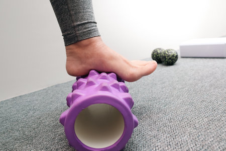 Female legs with roll small sports ball. Roller massager, self massage and healthy lifestyle. Myofascial relaxation of the muscles of the footの写真素材