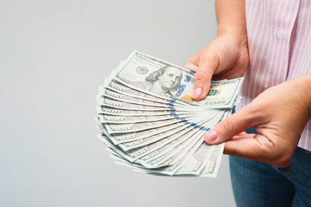 woman hands holding us dollar bills. Woman's hands shows a fan of money on white background.の写真素材