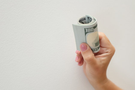 Roll of Dollar Bills in Hand. Hand Holding Rolled Up Dollar Bills on white backgroundの写真素材