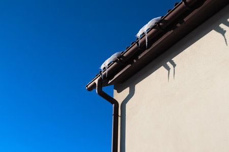 Icicles hanging from a roof. The edge of a roof covered by ice and icicles. House Roofの写真素材