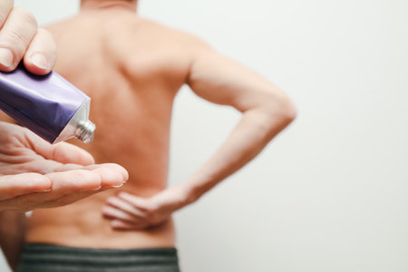 Male holding hand to point of back pain. Senior man having back pain. Woman hand covers man bare back.の写真素材