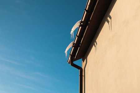 Icicles hanging from a roof. The edge of a roof covered by ice and icicles. Icicles, House Roofの写真素材