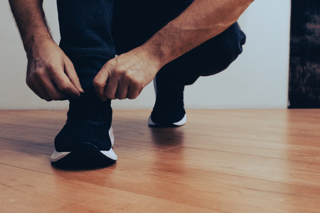 Running shoes man tying shoe laces. Athlete preparing to work out. Man tying jogging shoes. Man wearing shoes preparing for workoutの写真素材