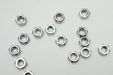 Metal nuts made of steel. Hexagon nuts scattered on white backgroundの写真素材