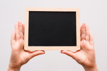 Woman's hand showing chalkboard. Place for writing text on a blackboard. Hands Holding a Blank...