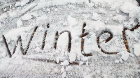 finger lettering winter on the snow on a wooden brown table. Hand writing in the snow.の写真素材