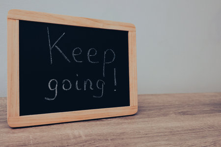 Keep going text written on wooden frame school blackboard. Handwritten text on a blackboardの写真素材