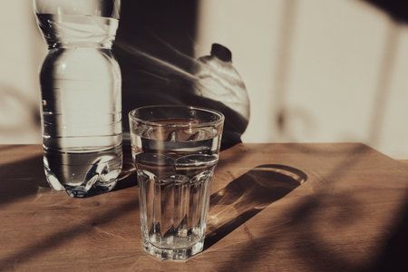 Mineral water blue plastic bottle in glass, with sunlight deep shadow of glass. Hard sunlight. Water...