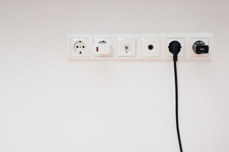 Modern Electrical Outlet. Electrical outlet, cable and electrical plug and the network cable interface on a white wall backgroundの写真素材