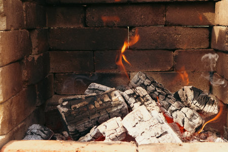 Fire with flames and embers on a barbecue. Stone barbecue. The fire is lit in a summer brick oven for barbecue, grill and other outdoor dishes.の写真素材