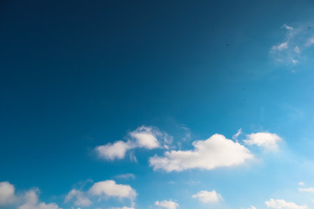 White clouds of different shapes in the blue sky. Serene blue background. Cloudscape on a bright sunny day. Cirrus Cloudscapesの写真素材