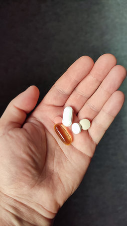 Pills, medicine and healthcare of senior man taking daily capsules and pills. Medication health care medical concept. Close up hand man taking multiple pills take a medicine in handの写真素材