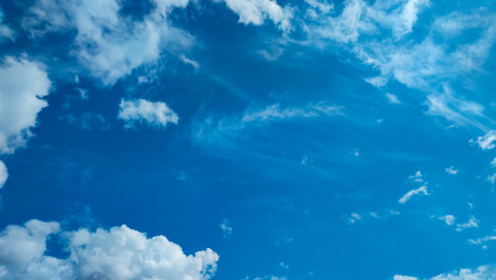 White clouds of different shapes in the blue sky. Serene blue background. Cloudscape on a bright sunny day. Cirrus Cloudscapesの写真素材