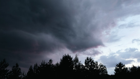Dramatic thunderstorm with dark clouds in the evening. Dramatic sky of clouds reflecting strong hues of orange, pink, blue and yellow lighting upの写真素材