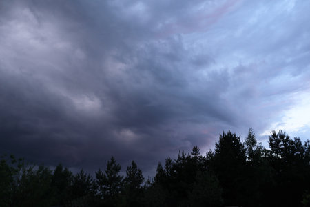 Dramatic thunderstorm with dark clouds in the evening. Dramatic sky of clouds reflecting strong hues of orange, pink, blue and yellow lighting upの写真素材