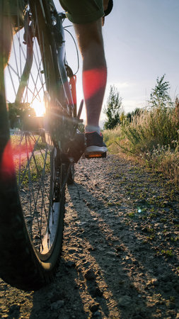 Silhouetted man on bike at sunset with space for text. Let's start adventure. Man riding bicycle on a gravel road at sunsetの写真素材