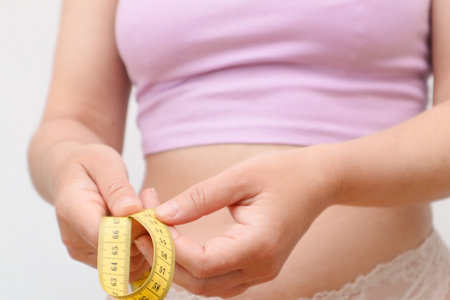Unrecognizable lady checking result of weight loss diet or liposuction. Overweight woman measuring her fat belly. Beauty, shape, healthy and health care female concept.の写真素材