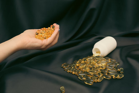 Omega 3 capsules being poured into hand for daily supplement intake. A woman's hand pours omega...