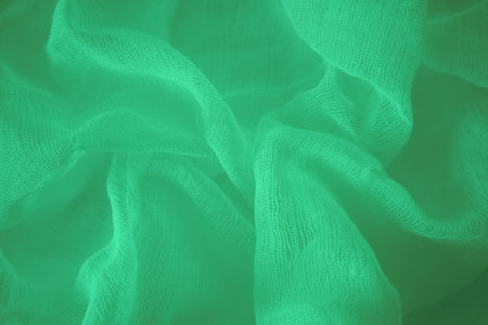 Teal silk fabric drapes, elegant waves, background, textile design. A close-up shot of a teal satin fabric, showing its smooth, glossy textureの写真素材