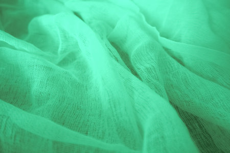 Teal silk fabric drapes, elegant waves, background, textile design. A close-up shot of a teal satin fabric, showing its smooth, glossy textureの写真素材