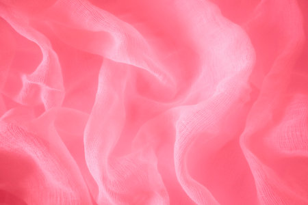 Red silk fabric drapes, elegant waves, background, textile design. A close-up shot of a red color satin fabric, showing its smooth, glossy textureの写真素材