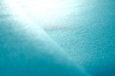 Close-up of blue silk fabric with soft folds and drapery. Perfect as an abstract background for fashion projects, branding, design, or advertising.の写真素材