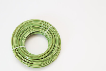 A new coil of bright green nylon trimmer line, neatly tied with a white cable tie, presented on a clean white surface. Essential consumable for brush cutters and grass trimmers for garden maintenance.の写真素材