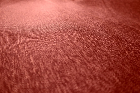 Close-up abstract texture of dark reddish-brown fabric or carpet material. The surface has a slightly fuzzy and uneven grain. Ideal as a background for design or presentation purposes.の写真素材