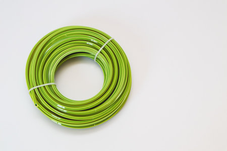 A new coil of bright green nylon trimmer line, neatly tied with a white cable tie, presented on a...