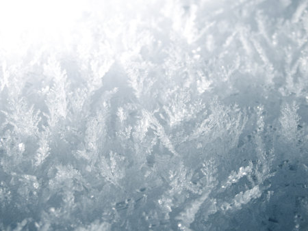 Close-up of delicate geometric ice formations and frost patterns glistening in bright winter light....
