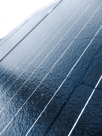 A close-up, angled view of a blue photovoltaic panel covered in frost and melting ice. Highlights the challenges of renewable energy maintenance during freezing winter weather.の写真素材