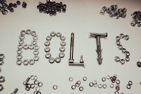 Creative composition of the word BOLTS made from hardware fasteners. Industrial background with...
