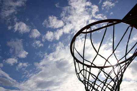 Silhouette of a basketball hoop against a brilliant sky.の写真素材