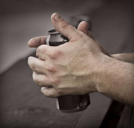 Working man's rough hands hold a can of beerの写真素材