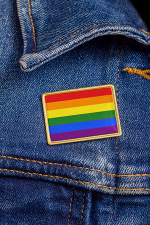 Gay pride flag pin on a denim jacket for LGBTQ identity, pride, and activism. The flag design is public domain for all uses.の写真素材